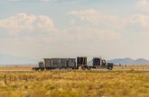 Semi-truck transporting cargo on a highway across a Colorado valley, showcasing logistics and transportation solutions by Smith Transport Solutions.