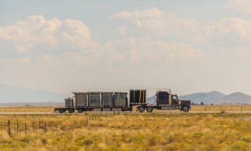 Semi-truck on a highway transporting freight across a Colorado valley, showcasing Smith Transport Solutions