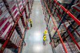 Warehouse workers in safety gear managing inventory among tall shelving units filled with cargo, illustrating efficient warehousing solutions by Smith Transport Solutions.